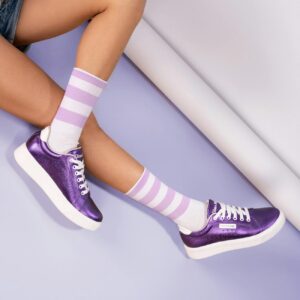 Close-up of purple sneakers and striped socks, highlighting trendy footwear fashion.